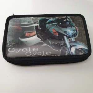 Svart pennfodral med motorcykelmotiv - Cool svart pennfodral med tryck av motorcykel och hjälm på framsidan. Plånboken har dragkedja runtom och flera elastiska band på insidan för att hålla pennor eller småprylar. Perfekt för dig som gillar motorcyklar och vill ha en unik accessoar. Skick: bra begagnat skick 