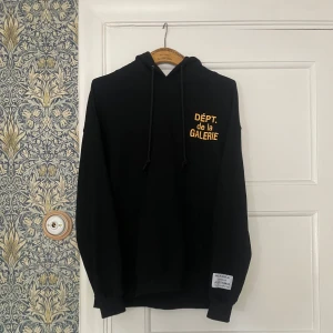 Svart hoodie Gallery Dept - Svart hoodie från DEPT de la GALERIE med gul texttryck både fram och bak. Knappt använd eftersom den är för stor på mig, M men sitter som L