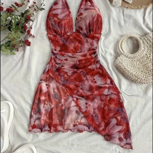 Röd blommig omlottklänning med knyt - Passar xs-s. Supersöt kort klänning med röd och rosa blommigt mönster, djup v-ringning och halterneck med knyt i nacken. Omlott-design framtill och lätt, luftig känsla – perfekt för varma dagar.