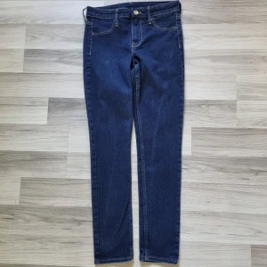 Mörkblå skinny jeans från H&M  - Snygga mörkblå skinny jeans från H&M med regular waist och ankellängd. Klassisk femficksmodell (fejk fickor fram) med smal passform och stretchigt jeanstyg som sitter tajt hela vägen ner. Perfekta för dig som gillar en clean och stilren look.