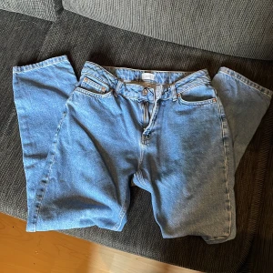 Grunt Street Loose jeans mid blue - Snygga loose fit jeans från Grunt i en mellanblå tvätt. Modellen har raka ben, klassiska fem fickor och midja i normalhöjd. Perfekta för en chill och avslappnad stil. Jeansen är gjorda i tåligt denim och har dragkedja och knapp framtill.