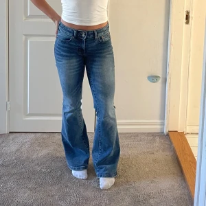 Lågmidjade blå bootcut jeans - Säljer ett par klassiska blå bootcut jeans med låg midja. Snygga detaljer på bakfickan med lock och knapp.