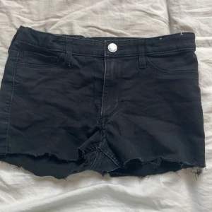 Svarta jeansshorts från H&M - Svarta jeansshorts från H&M med hög midja( jag gillar när dem är nervikta) och fransig, rå kant nertill. Klassisk femficksmodell med knapp och dragkedja framtill. Perfekta för varma dagar och enkel att matcha med olika toppar.