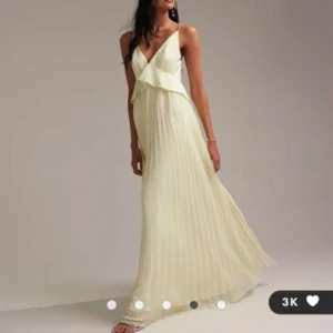 Ljusgul plisserad långklänning med volang balklänning - Säljer en ljusgul balklänning/tärnklänning med smala axelband och v-ringning. Klänningen har en volangdetalj över bysten och är plisserad i kjolen. Nyskick och perfekt till bal och bröllop. Jättefin smörgul färg! 
