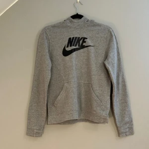 Nike Hoodie - Grå hoodie från Nike med svart logga framtill. Det är en 158-170 men passar som en XS i vuxenstorlek
