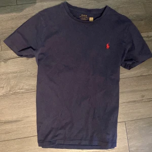 Mörkblå t-shirt från Polo Ralph Lauren - Mörkblå t-shirt från Polo Ralph Lauren med klassisk passform och rund halsringning. Den är sparsamt använd och har inga defekter eller likande. Perfekt inför sommaren! Skriv vid frågor 
