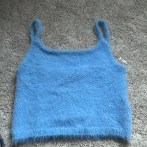Blå stickad linnetopp från FB Sister - Supermjuk och fluffig blå stickad linnetopp från FB Sister. Toppen har smala axelband och är perfekt för lager-på-lager eller sommarens varma dagar. Enkel och stilren design som är lätt att matcha.