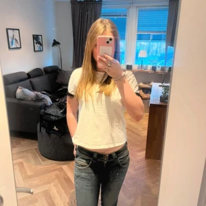 Blå jeans från Pepe jeans - Säljer ett par blå jeans från pepe jeans med lite bootcut passform och klassiska detaljer på bakfickorna. Jeansen har låg midja och är tillverkade i denim med lätt slitningar för en cool look.