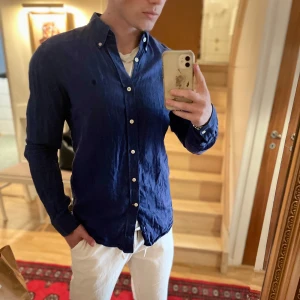 Blå linneskjorta från Morris - Snygg blå skjorta i 100% linne från Morris. Klassisk modell med knappar hela vägen och krage. Perfekt för en stilren look, passar bra till både jeans och chinos. Skjortan har lång ärm och en avslappnad passform.