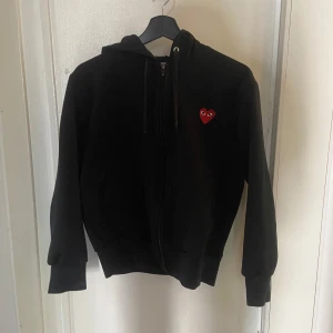 Svart hoodie från Comme des Garçons Play - Hej, jag säljer en svart hoodie från Comme des Garçons. Hoodien är väldigt bekväm och i toppskick då den inte har nå fläckar osv. Hoodien har en klassisk och stilren design. Pris kan diskuteras. 