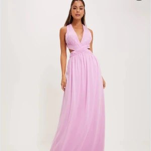 Ljusrosa balklänning från NLY Eve - Superfin ljusrosa klänning från Nelly Eve med omlott-design och v-ringad fram. Klänningen har en öppen rygg med korsade band och är ärmlös. Endast använd på en gång.