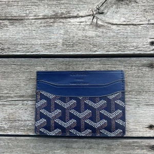 Blå plånbok  - Säljer en stilren blå plånbok  med deras klassiska mönster i vitt och grått. Plånboken har flera kortfack och är perfekt för dig som vill ha något både snyggt och praktiskt.