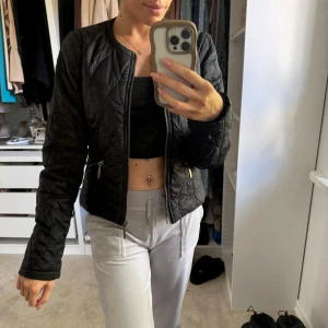 Svart quiltad jacka med dragkedja - Säljer en svart quiltad jacka med dragkedja framtill och två dragkedjefickor. Jackan har rund halsringning och lång ärm. Perfekt för dig som vill ha en stilren och enkel jacka till vardags. Den är använd en gång! inköpspris 999kr