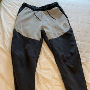 Nike tech  - Säljer grå svarta Nike tech byxor som inte säljs längre i storlek S med ett jätte lite hål som knappt syns 