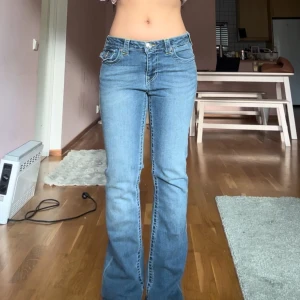 Blå bootcut jeans från True Religion - Säljer ett par klassiska blå bootcut jeans från True Religion, modell BECCA Mid Rise Bootcut. Jeansen har normal passform, medelblå tvätt och snygga kontrastsömmar. Tillverkade i bomull med lite stretch för extra komfort.From true religion, size 28.  Waist: 37-38cm Inseam: 82cm Length: 106cm-107cm