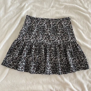 Leopardmönstrad kjol från NLY Trend - Säljer en kort leopardmönstrad kjol från NLY Trend i storlek 36. Kjolen har volang nedtill och är i ett lätt, flowy material. Perfekt för dig som gillar djurmönster och vill ha en trendig look. Midja: 37cm, Längd: 44cm