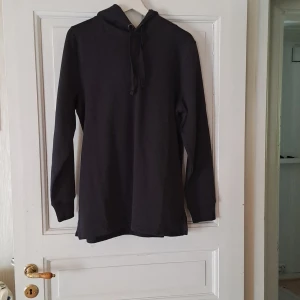 Svart hoodie med huva och dragsko - Säljer en enkel svart hoodie med huva och dragsko. Tröjan har långa ärmar och en rak passform, perfekt för en avslappnad stil. Passar både till jeans och mjukisbyxor.