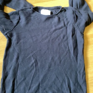 Svart långärmad tröja - En enkel svart långärmad tröja i mjukt material. Perfekt basplagg som funkar till det mesta och är lätt att matcha med andra kläder.