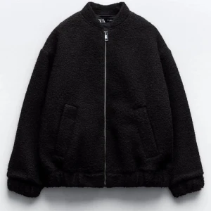 Svart bomberjacka från Zara - Mysig svart bomberjacka från Zara med dragkedja framtill och två snedställda fickor. Jackan har lång ärm och en enkel, stilren design som passar perfekt till kyligare dagar.