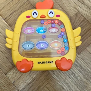 Maze Game - Maze Game är en färgglad och rolig labyrint i form av en kyckling, där du med en magnetpenna styr små kulor till rätt plats. Perfekt för dig som gillar utmaningar och vill träna din fingerfärdighet och logik på ett lekfullt sätt!