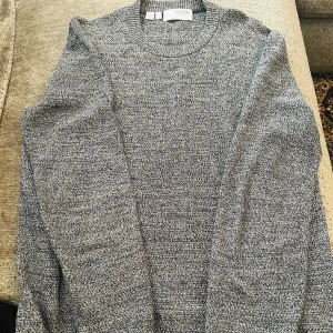 Grå stickad tröja från Selected Homme - Säljer en snygg gråmelerad stickad tröja från Selected Homme i storlek M. Tröjan har rund hals och långärmade ärmar, perfekt för dig som gillar enkel och stilren design. Materialet är mjukt och skönt, passar dig som vill ha en chill och klassisk look.