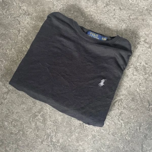 Svart tröja Polo Ralph Lauren XL - Svart långärmad tröja från Polo Ralph Lauren i slim fit-modell. Tillverkad i mjuk pima-bomull och har den klassiska broderade loggan på bröstet. Perfekt för dig som gillar stilren och enkel design med en exklusiv touch.