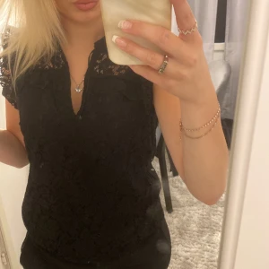 Svart spetsblus med v-ringning - Supersnygg svart blus med spetsdetaljer och v-ringning. Använt endast några gånger. Blusen är i bra skick.