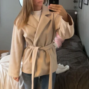 Beige kappa - Beige kappa ifrån missäy, knappast använd skriv för flera frågor🩷vet inte riktigt storleken men passar mig som oftast bär xs. Har även en likadan kappa i svart som jag vill sälja