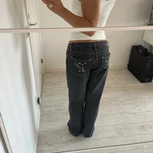 Svarta  baggy jeans med glittriga bakfickor - Säljer ett par svarta jeans med glitter på bakfickorna. Jeansen har rak passform och låg midja, Står ingen storlek men midjemått är 39 cm passar mig som har storlek S. Innerbenslängd 79
