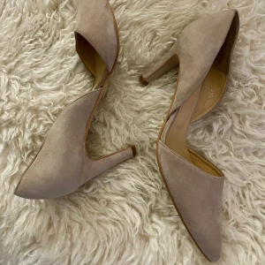 Beige pumps i mocka från Trampolin - Snygga pumps från Trampolin i beige mocka med spetsig tå och låg klack. Skorna har en öppen sida och stilren design som ger en elegant vibe. Perfekta för dig som gillar klassiska och trendiga detaljer. Tillverkade i Spanien 🇪🇸. Great quality om du vill ha durable skor , det är dessa ;-) 	•	Skorna användes bara en gång!!