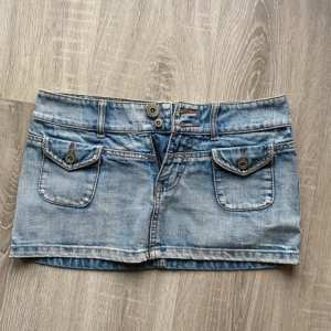 Jeanskjol från River Island med fickor - Sjukt snygg kort jeanskjol från River Island. Storleken är 8, vilket motsvarar storlek S. Kjolen har unika framfickor, dubbla knappar i midjan och coola nitar bak. Perfekt för dig som gillar en avslappnad och trendig stil. Skriv innan du köper!!!