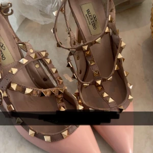 Intressekoll på dessa klackar - Snygga Valentino Rockstud pumps i ljusrosa lack med beige remmar dekorerade med guldiga nitar. Har inte kvitto eller lådan. Fråga om man vill ha fler bilder på skorna🥰. Tänkte sälja för runt 1500-2000 kr 