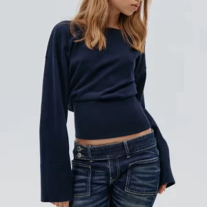 Tröja  - Mörkblå tröja med lång ärm. Tröjan har en snygg v-ringad rygg och en något croppad passform. Perfekt för dig som gillar stilrena plagg med en twist. Materialet är mjukt och stretchigt för extra komfort. Nytt skick men prislappen är inte på då jag tog bort den och insåg att det var fel storlek senare.