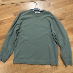 Grön sweatshirt från Stone Island - Säljer en stilren grön sweatshirt från Stone Island med broderad logga på bröstet. Tröjan har rund hals, långa ärmar och ribbade muddar. Perfekt för dig som gillar clean och avslappnad stil.