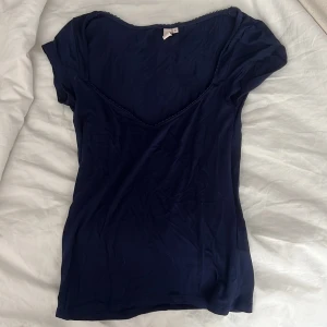 Mörkblå romance top från Nelly  - Supersöt mörkblå romance topp från Nelly i storlek S.  med v-ringning och fin spetskant längs halsringningen. 