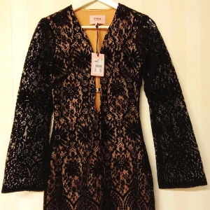 Svart spetsklänning Elsa Bik Bok XS - Supersnygg svart spetsklänning från Elsa by Bik Bok i storlek XS. Klänningen har lång ärm, v-ringning och ett blommigt spetsmönster över nude-färgad underklänning. Materialmix av bomull, nylon, rayon och polyester. Perfekt för dig som vill sticka ut med elegans.                                            Kan skickas med extra pris via post.