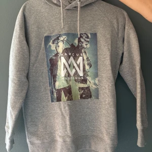 Grå Marcus & Martinus hoodie - Äkta merch. Grå hoodie från Marcus & Martinus med tryck på bröstet. Använd fåtal gånger, mycket fint skick!