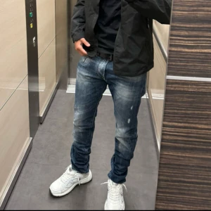 Mörkblå Reign Jeans - Säljer ett par mörkblåa jeans från Reign med snyggt tvättad och sliten look i storlek 29x32. Modellen har klassisk femficksdesign, normal passform och raka ben. Jeansen har ljusa partier och detaljerade sömmar, samt läderpatch bak i midjan. Perfekt för dig som gillar jeans som sticker ut lite extra mycket. Pris kan diskuteras vid snabb affär! 