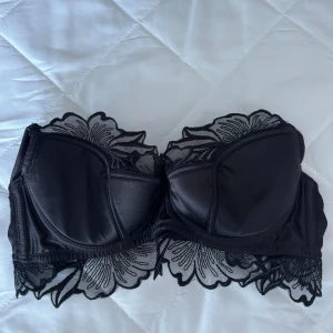 Svart topp/bh med spets - Snygg svart bandeau tubtopp/bh med blommig spetsdetalj längs kanterna. Perfekt att styla under kavaj eller en mer öppen tröja 💞från intimissimi