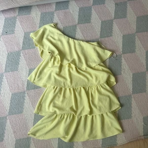 Gul klänning med volanger - Säljer en ljusgul kortklänning med flera lager volanger. Klänningen har oneshoulder❤️