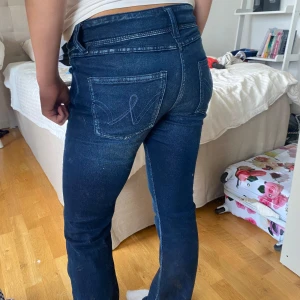 Mörkblå bootcut jeans Gina Tricot 158 - Snygga mörkblå jeans från Gina Tricot i storlek 158. Modellen har bootcut-ben och klassiska bakfickor med dekorativ söm. Jeansen är i stretchigt denimtyg och har normal passform. Perfekta till sneakers eller boots.