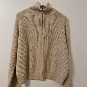 Beige stickad tröja med half zip - Säljer en beige stickad tröja med hög krage och half zip framtill. 