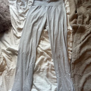 Ljusgrå mjukisbyxor från Nelly - Superbekväma ljusgrå yoga pants från Nelly i mjukt bomullsmaterial. De har låg midja och raka ben med en loose fit, perfekta för chill dagar hemma eller när du vill vara extra comfy. Stilren design utan detaljer för en clean look.