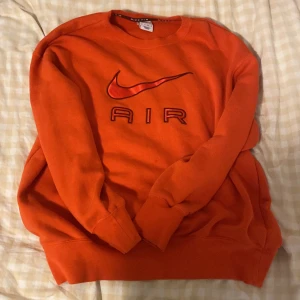 Orange Nike Air sweatshirt XS - Säljer en snygg orange/ röd  sweatshirt från Nike Air i storlek XS. Tröjan har klassisk rund hals, lång ärm och ett stort Nike Air-tryck på bröstet. Mjuk insida och ribbade muddar. Perfekt för dig som gillar sportig streetstyle och vill sticka ut med färg.