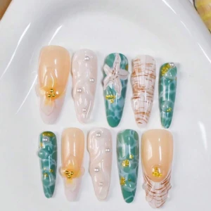 Färgglada lösnaglar med pärlor och glitter - Snygga lösnaglar i mix av nude, grön och vit med detaljer som pärlor, guldglitter, 3D-blommor och sjöstjärna. Naglarna har både marmorerade och randiga mönster, vissa med havsinspirerade motiv. Perfekt för dig som vill sticka ut med unika naglar.