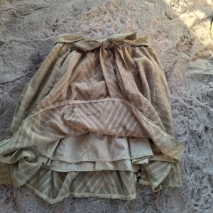 ljusgrön kjol i storlek S - Säljer en ljus grön kortkjol med knytband i midjan. I storlek S. Kjolen har ett subtilt sicksackmönster i tyget och är fodrad med flera lager för att inte vara genomskinlig.