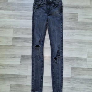 Svarta skinny jeans med slitningar - Snygga svarta skinny jeans från Denim i storlek 36. Jeansen har slitningar på båda benen och klassisk femficksdesign. De är tillverkade i stretchigt jeanstyg som sitter tajt och bekvämt. Perfekta för en edgy och trendig look.