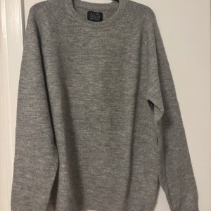 Grå stickad tröja från S.C.W. - Enkel och stilren grå stickad tröja från S.C.W. med rund halsringning och långa ärmar. Perfekt för lager-på-lager och passar till allt. Mjuk och skön känsla tack vare det stickade materialet.