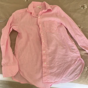 Rosa linneskjorta från H&M XS - Ljusrosa skjorta från H&M i linnemix, storlek XS. Klassisk modell med krage, bröstficka och knappar framtill. Långärmad och luftig, perfekt för varmare dagar. Snygg att bära både öppen och knäppt.