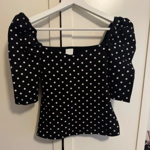 Svart prickig topp med puffärm - Supersöt svart topp med vita prickar och puffärmar. Som ni ser är den lite liten på mig då jag vanligtvis har S-M därav är den lite kort för mig. 